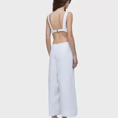 Mulher de costas com top e calças brancas, sandálias e óculos escuros