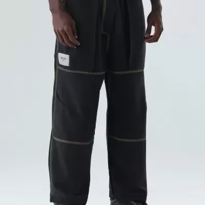 Calças pretas largas com costuras verdes e etiqueta branca