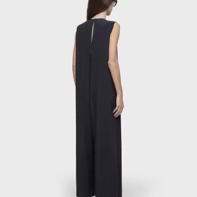 Macacão preto comprido sem mangas com fenda nas costas, usado com sandálias pretas