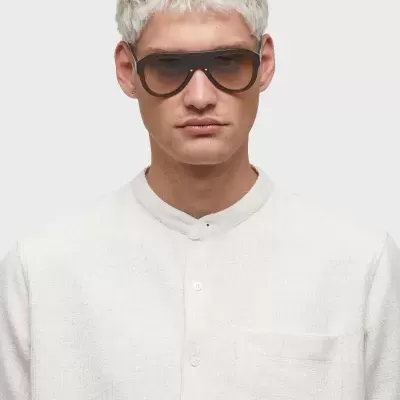 Homem com óculos de sol de armação preta e camisa branca texturizada