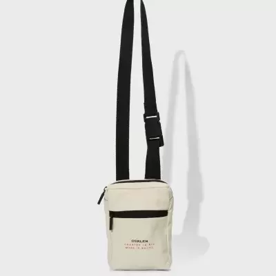 Bolsa pequena bege com alça preta ajustável e texto na frente