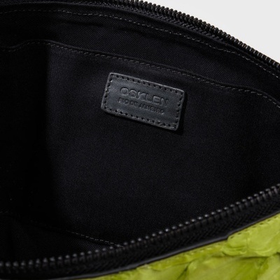 Interior de bolsa preta com etiqueta OSKLEN ECO LEATHER e exterior verde texturizado