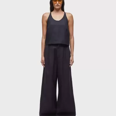 Mulher com top preto, calças largas pretas e óculos de sol amarelados