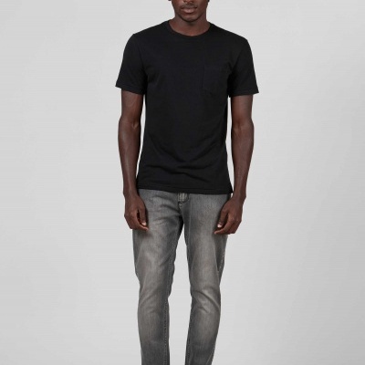 Homem com t-shirt preta, jeans cinza dobrado e sapatilhas pretas