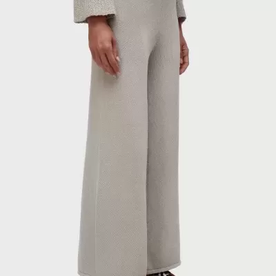 Calças largas de malha bege com cós elástico e sapatos slip-on com padrão leopardo.