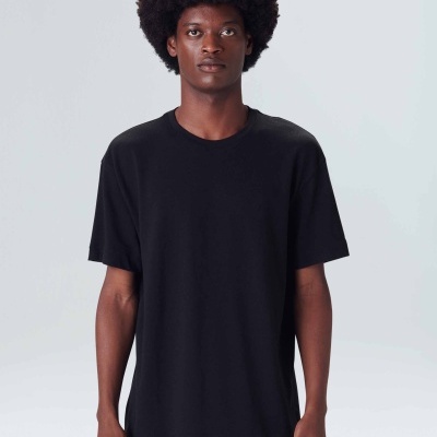 Homem a usar t-shirt preta de manga curta com acabamento desfiado na bainha e calças bege