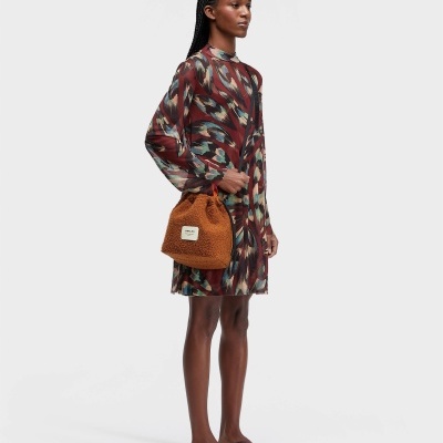 Mulher com vestido estampado, bolsa castanha e sandálias castanhas