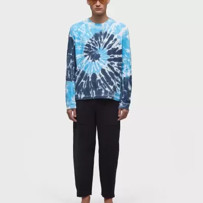 Homem com camisola tie-dye azul, calças pretas e sandálias