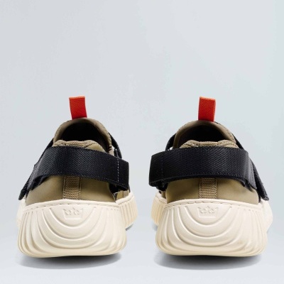 Sapatilhas castanhas e pretas com solas brancas e tiras pretas