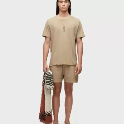 Homem com roupa bege e cachecol com padrão de folhas