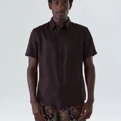 Homem com camisa de mangas curtas castanha e calções florais coloridos