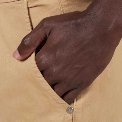 Bolso lateral de calças bege com mão escura dentro