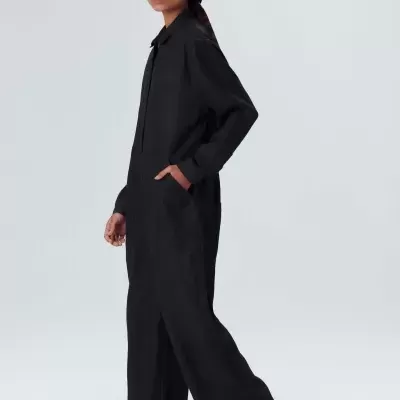 Mulher a usar macacão preto de manga comprida e calças largas com bolso lateral.