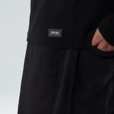 Peça de vestuário preta com etiqueta 'OSKLEN ECO & MINIMAL' em tecido canelado