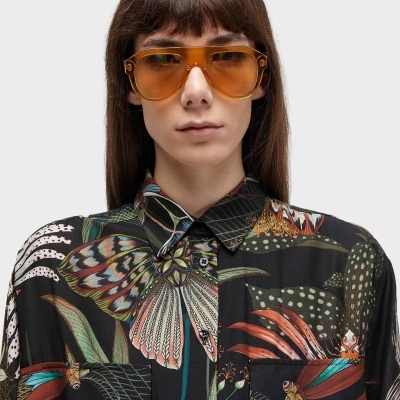 Óculos de sol âmbar e camisa preta com padrão colorido