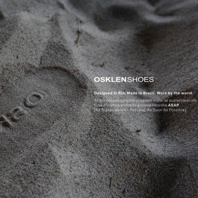 Imagem de areia com marcas de pegadas e texto da marca OSKLEN SHOES sobre materiais sustentáveis.