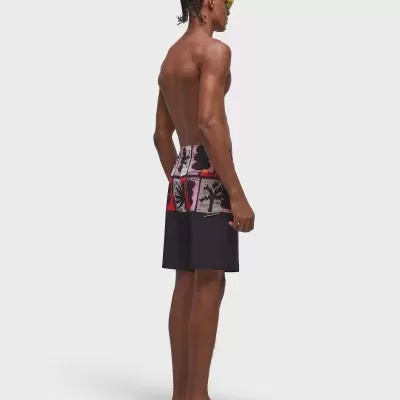 Homem com calções de banho coloridos em patchwork, óculos amarelos e chinelos pretos