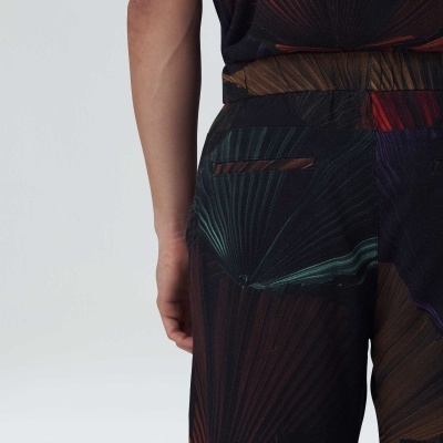 Pessoa vestindo conjunto com padrão abstrato colorido num fundo cinza claro