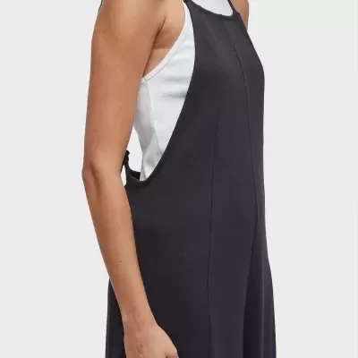 Vestido preto com alças finas usado sobre t-shirt branca sem mangas