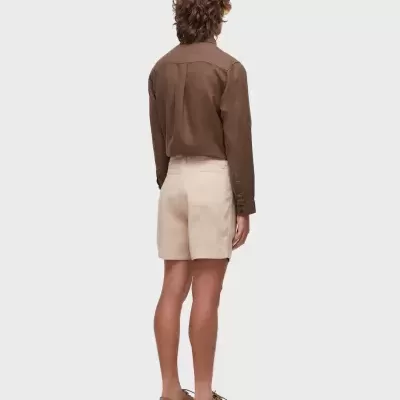 Homem de costas com camisa castanha, calções bege e sapatos castanhos