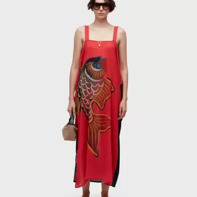 Vestido vermelho comprido com estampa de peixe colorido em modelo com óculos escuros.