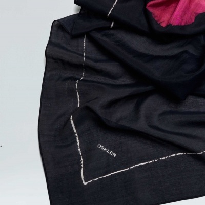 Lenço preto com padrão branco e texto OSKLEN, parte superior em tons de rosa e vermelho.