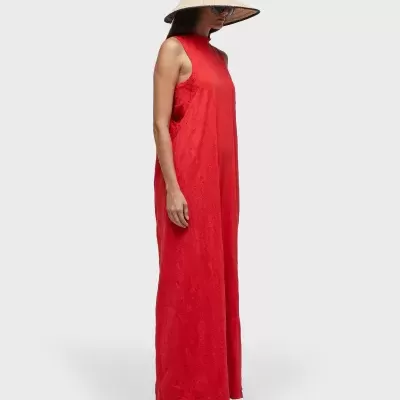 Vestido longo vermelho sem mangas usado por mulher com chapéu de palha e óculos.
