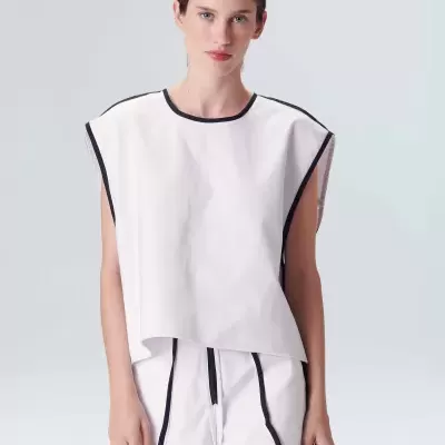 Mulher a usar conjunto branco com detalhes em preto sobre fundo branco