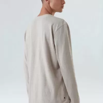 Homem de costas usando camisola bege de manga comprida e gola redonda