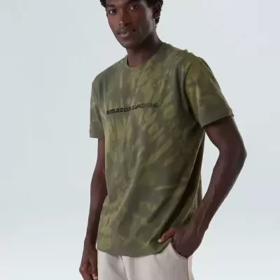 Camiseta verde camuflada com texto amazon GUARDIANS no peito, modelo masculino de pé, fundo cinzento claro