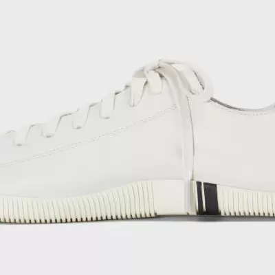 Ténis branco com sola branca e detalhes pretos.