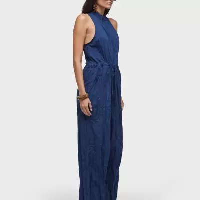 Macacão azul escuro sem mangas com cordão na cintura, usado com óculos e ténis brancos