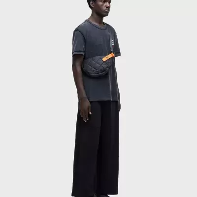 Homem com mochila preta acolchoada e t-shirt cinza