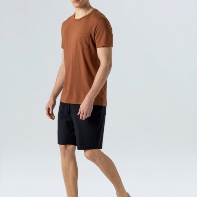 Homem com t-shirt castanha, calções pretos e sapatos slip-on pretos