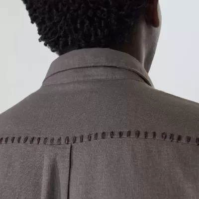 Parte de trás de camisa cinzenta com costura decorativa vermelha no ombro