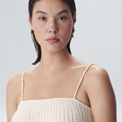 Mulher com vestido branco de malha e brincos dourados
