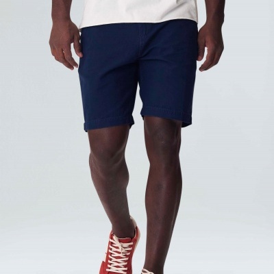 Homem com bermuda azul escura e sapatos vermelhos com atacadores brancos