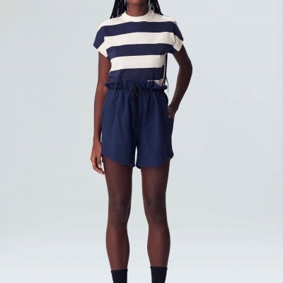 Mulher a usar t-shirt riscada branca e azul, calções azuis, chapéu preto, meias e ténis pretos