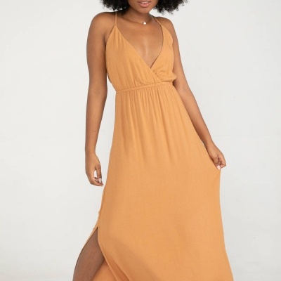 Vestido comprido laranja claro com alças finas e abertura lateral, usado com sandálias de cunha brancas