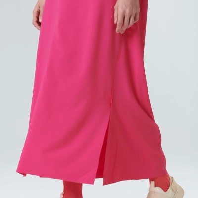 Vestido rosa choque comprido com racha lateral e sandálias bege com meias cor de rosa choque