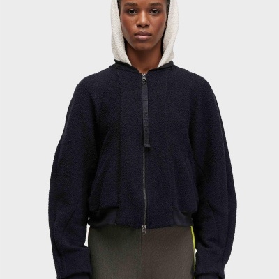 Casaco hoodie preto com capuz branco felpudo e calças castanhas com riscas laterais