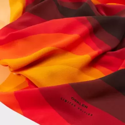 Pano de tecido colorido com padrão em vermelho, laranja, amarelo e castanho com texto OSKLEN LIMITED EDITION.