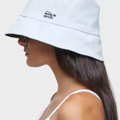 Chapéu bucket branco com texto bordado 'CHAPÉU MADE IN BRAZIL' usado por mulher.