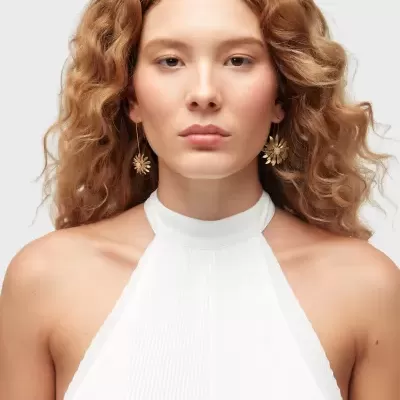 Mulher com pendentes dourados em forma de flor e vestido branco