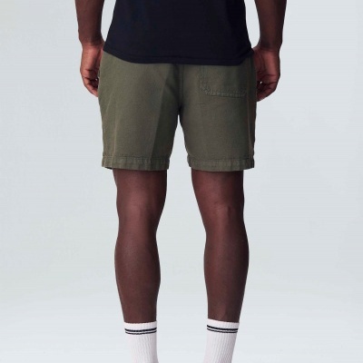 Vista traseira de homem com calções verde-oliva, t-shirt preta, meias e ténis brancos