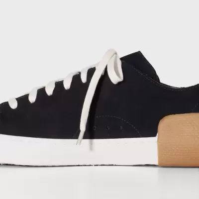 Tênis preto em camurça com sola branca e detalhe castanho