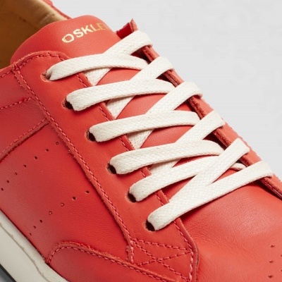 Ténis vermelho em pele com detalhes dourados e atacadores brancos