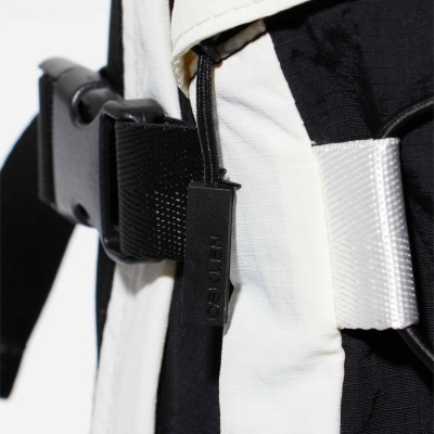 Mochila preta e branca com correias e etiqueta OSKLEN