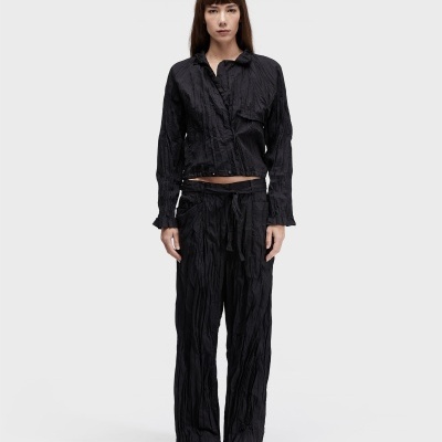 Mulher com conjunto preto enrugado e calçado branco fofa