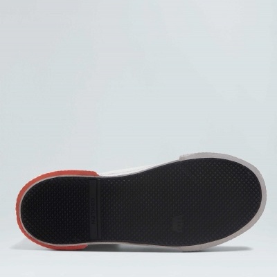 Sola preta de sapato com borda cinza e detalhe vermelho numa superfície cinzenta